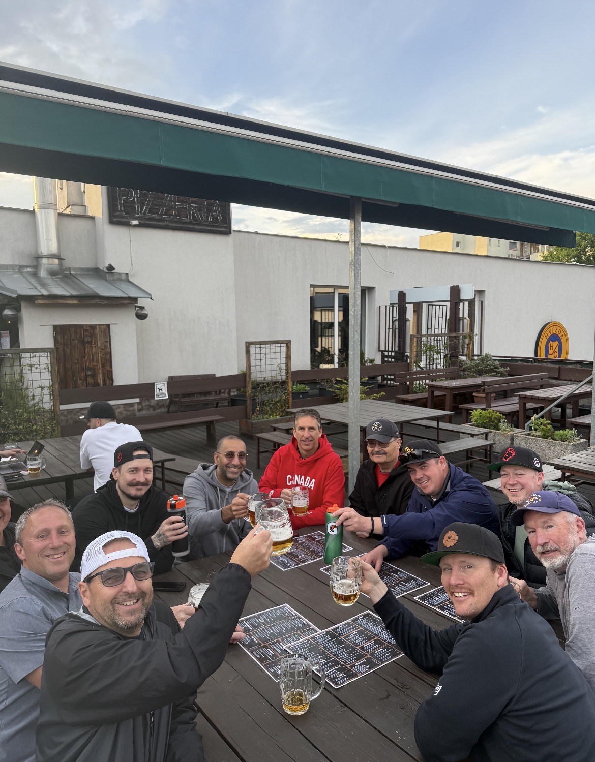 Rusty Mitts teammates raising a toast on a Prague rooftop pizzeria